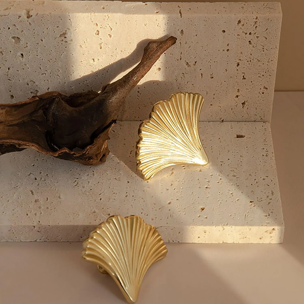 Brass Essence polished gold ginkgo leaf cabinet pull mounted on a wooden cabinet drawer, showcasing elegant leaf design and shiny finish.