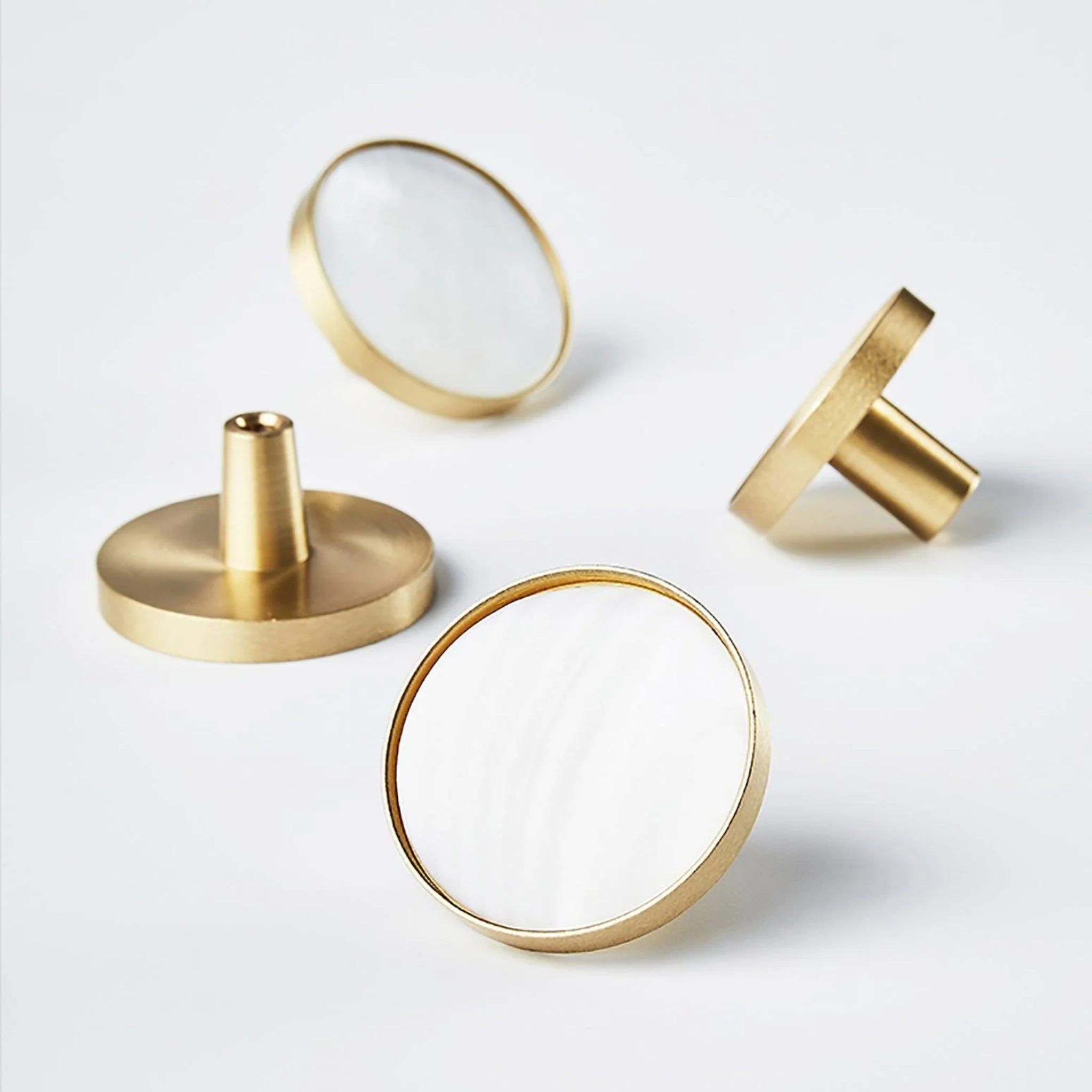 Mother of pearl and brass round cabinet knob by Brass Essence, showcasing a glossy pearl surface with brass accents.