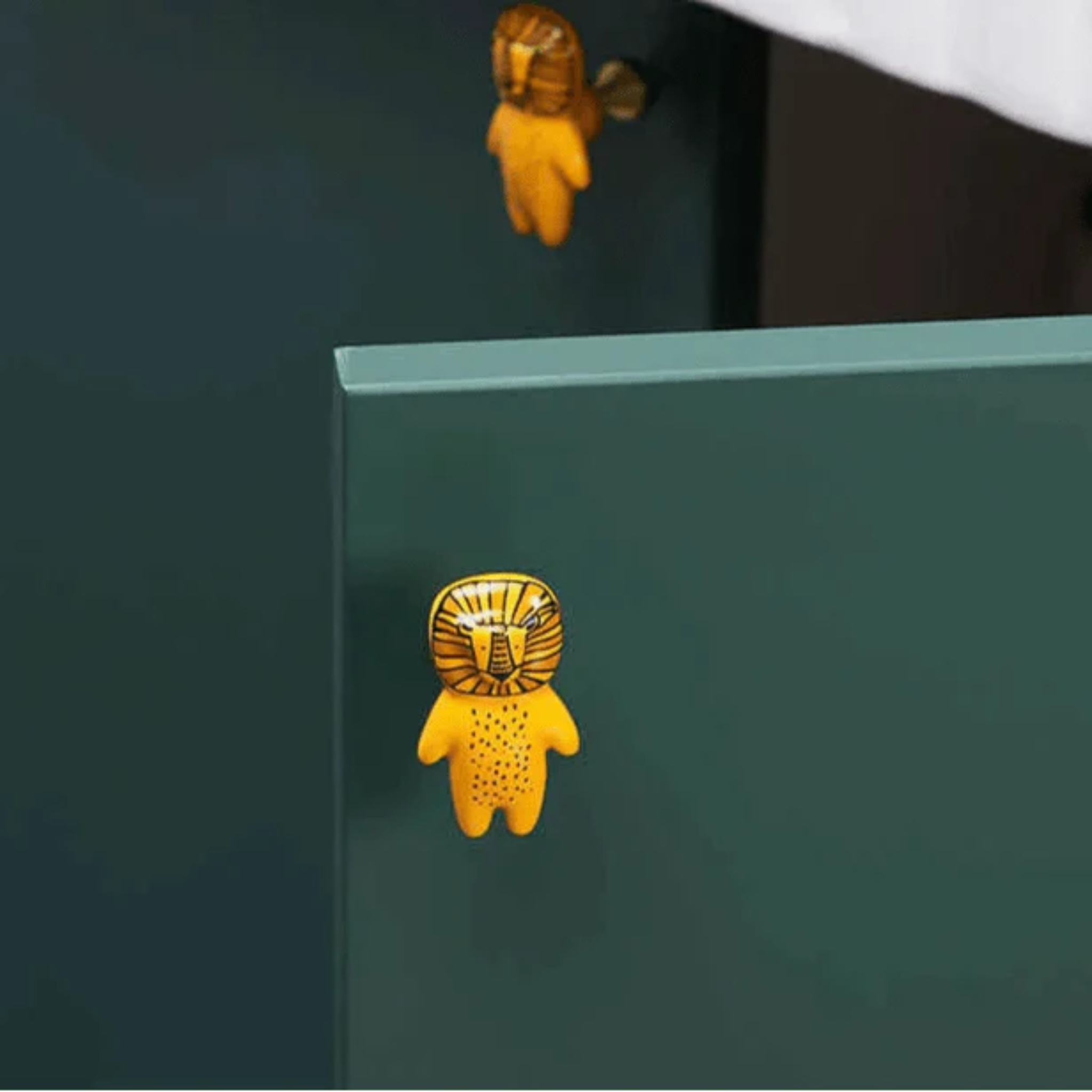 Brass Essence ceramic animal cabinet pull featuring a detailed animal design from the collection, mounted on a cabinet door.