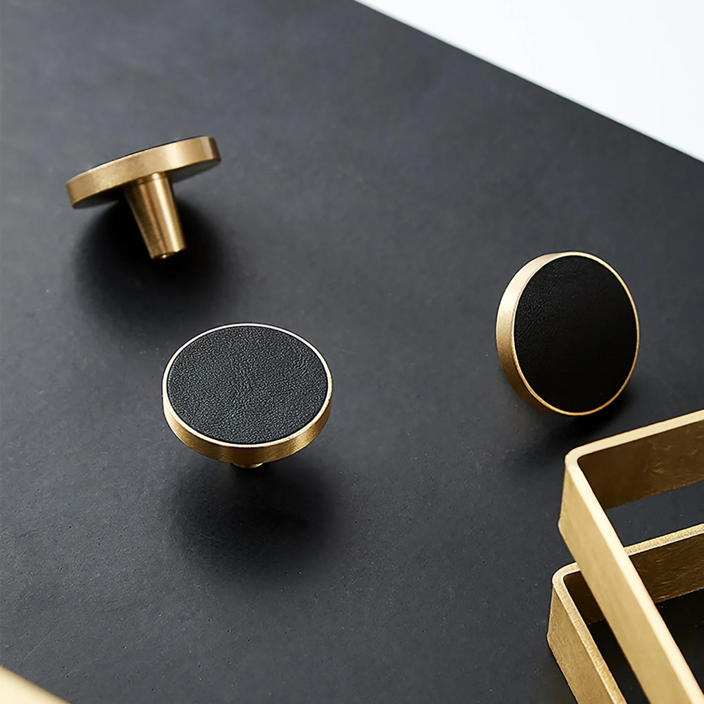 Brass Essence brushed brass and leather round handle, showcasing smooth brass surface and a leather grip on a modern furniture piece.
