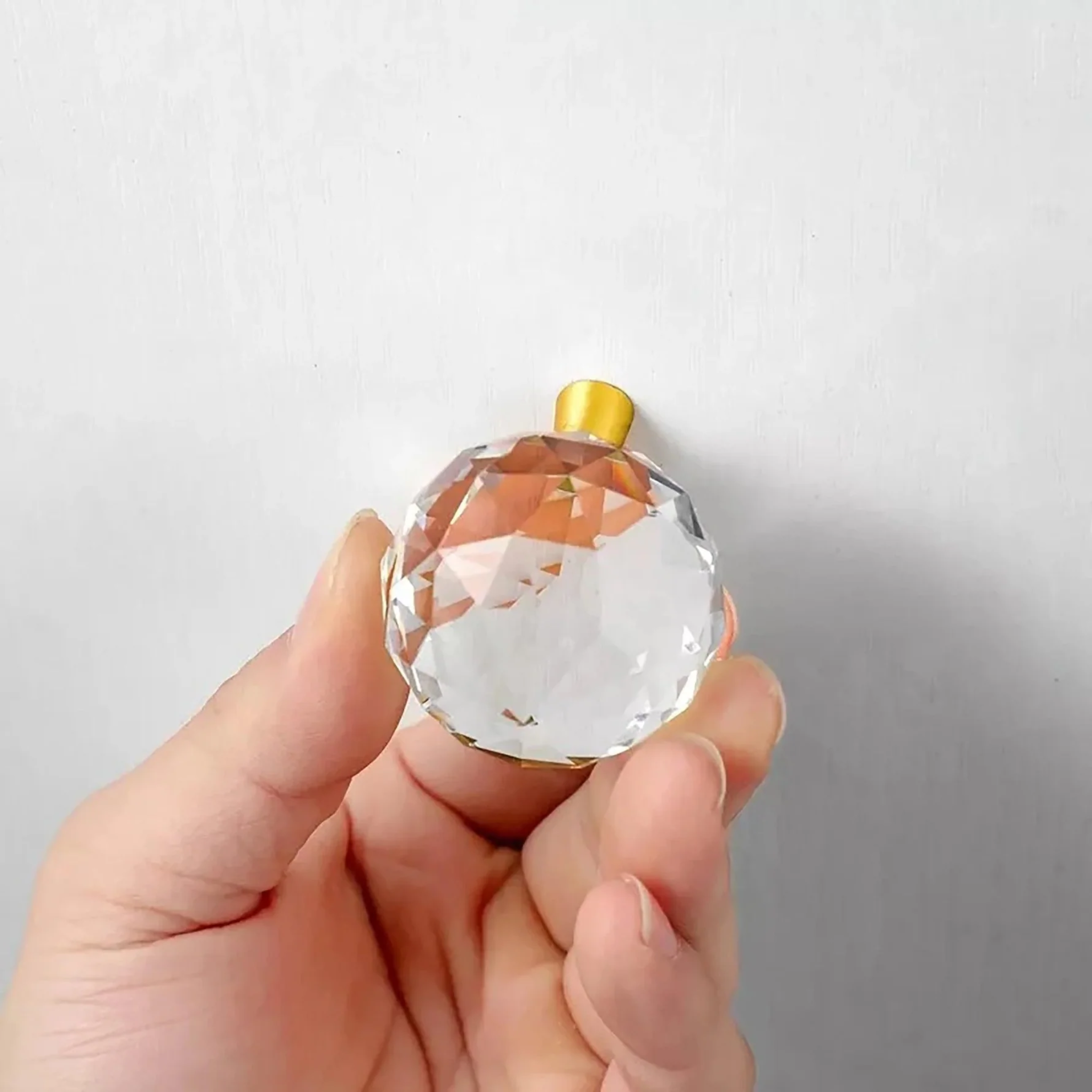 Faceted crystal and brass cabinet knob by Brass Essence, showcasing a sparkling crystal with polished brass hardware.