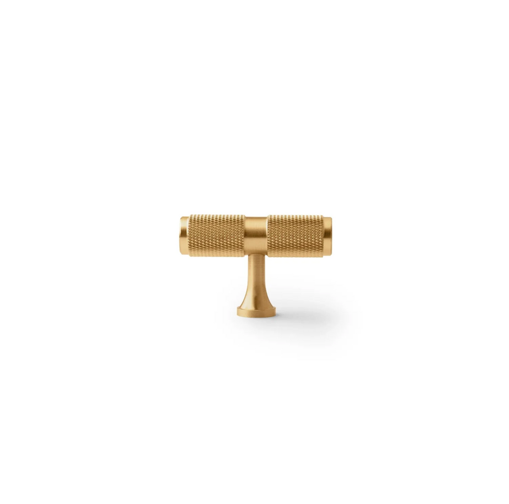 Yashvite knurled brass cabinet handle from Brass Essence collection, showing a close-up of the textured, polished brass handle on a cabinet door.