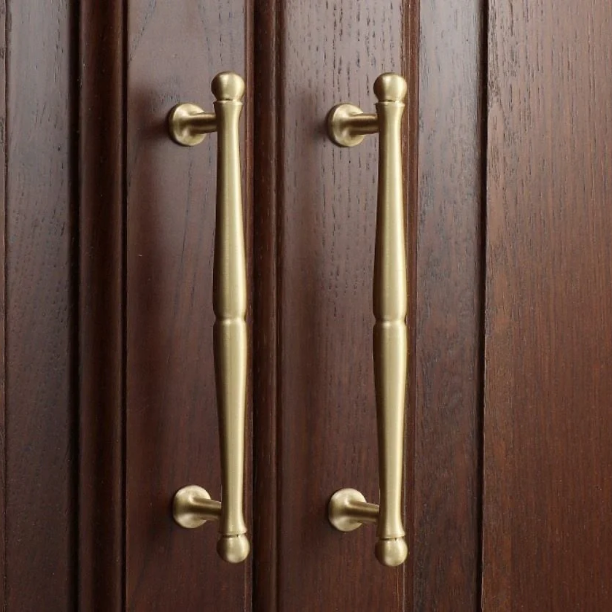 Brass essence Nishilia tapered brass cabinet handle from collection B-0069, featuring a sleek, modern design on a wooden cabinet.