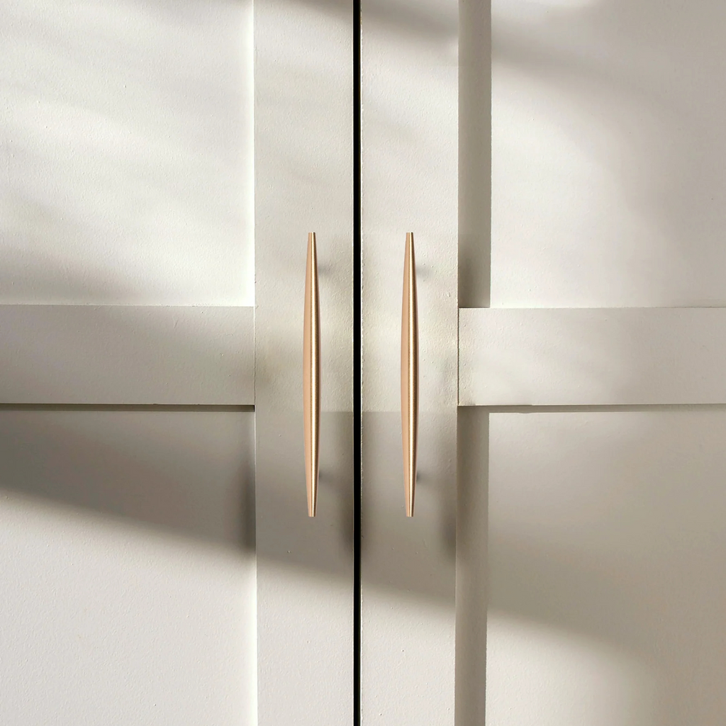 Brass Essence tapered brass spindle cabinet pull with rounded handle and mounting screws for furniture drawers and cabinets.