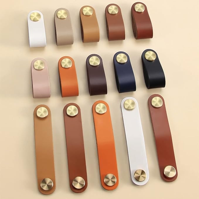 Brass essence leather and brass strap cabinet pulls, featuring a sleek design and sturdy brass hardware on a wooden cabinet.