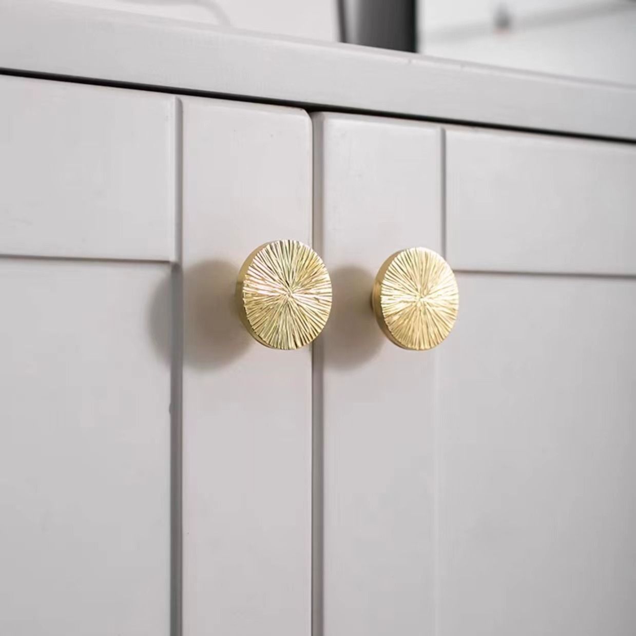 Pair of hammered brass half-circle pulls from Brass Essence, showing textured finish and sleek curved design for furniture or cabinets.