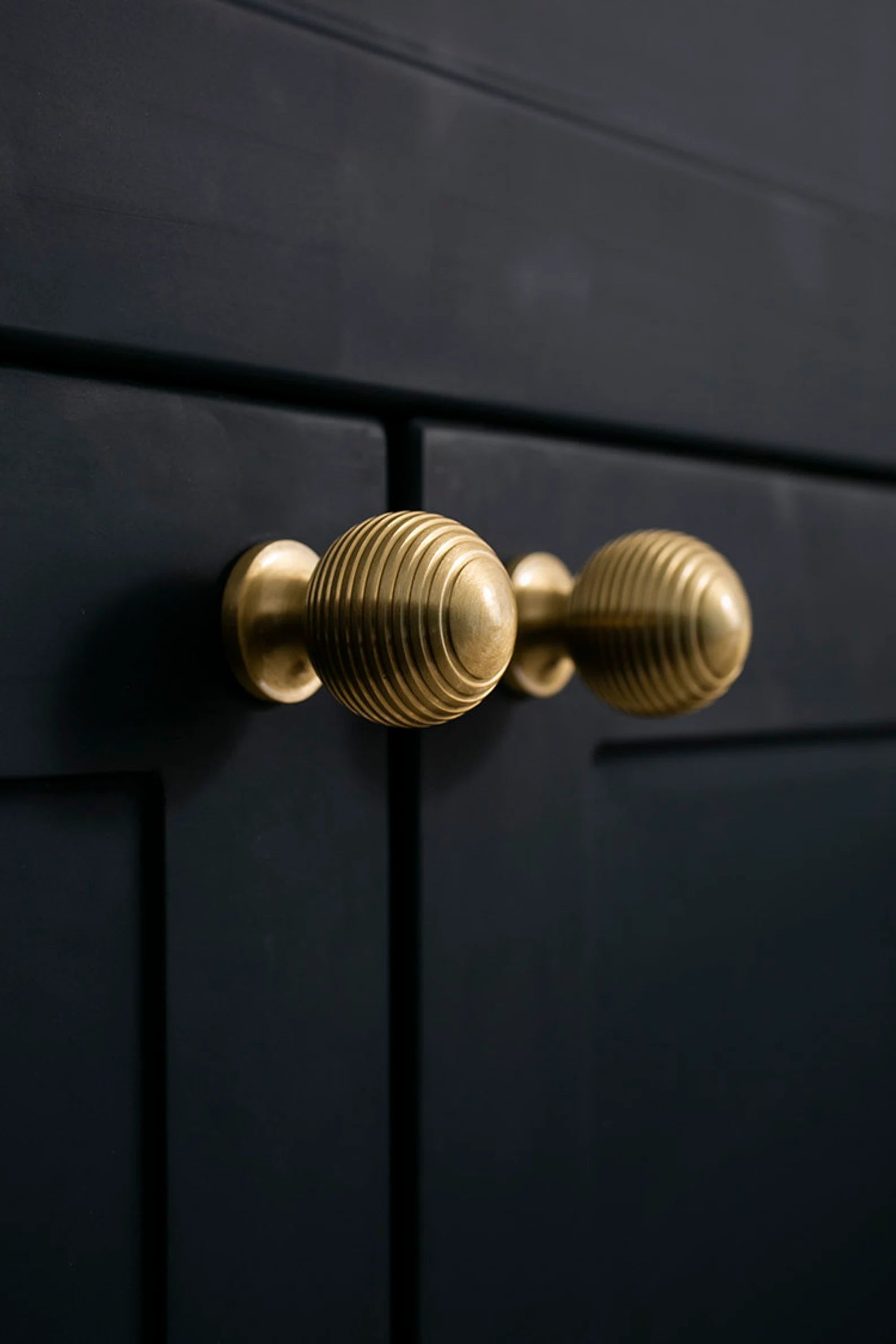 Alexander & Wicks Brass Knob by Brass Essence with a luxurious brushed finish, shown on a dark wooden cabinet.