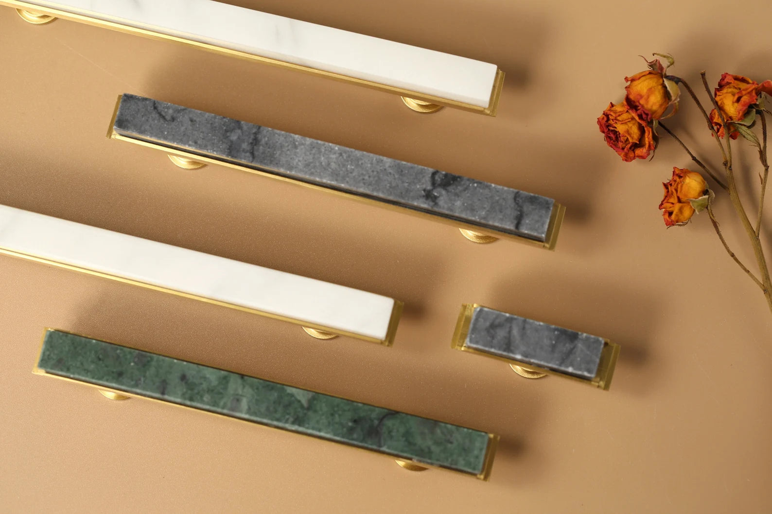 Modern white marble and brass T-bar handle by Brass Essence, featuring sleek design and polished finish on a contemporary furniture piece.